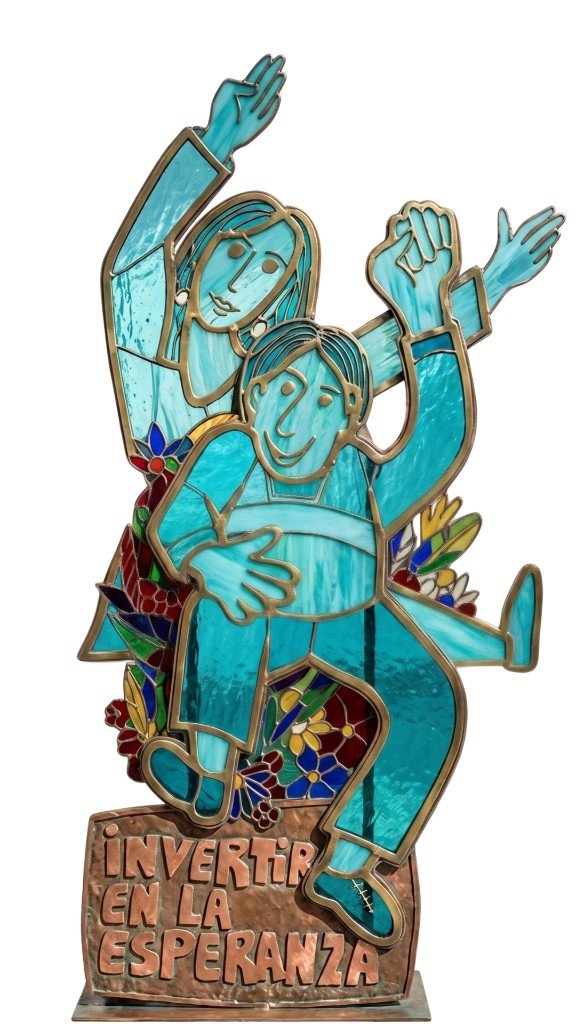 Vitral decorativo con figuras y flores; base con el lema «Invertir en la esperanza»